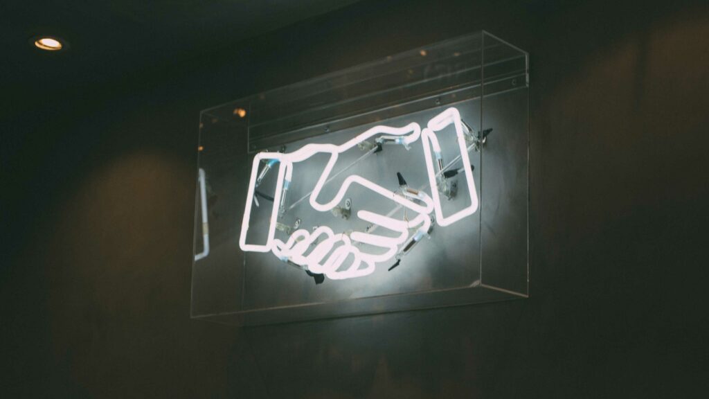 Ein Kunstobjekt, das einen Handschlag mit Neonleuchten darstellt.
