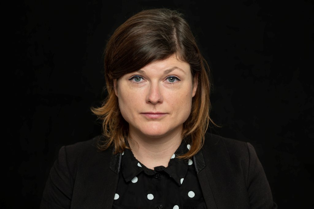 Porträt von Tina Lorenz in schwarzer Kleidung mit weißen Punkten vor schwarzem Hintergrund