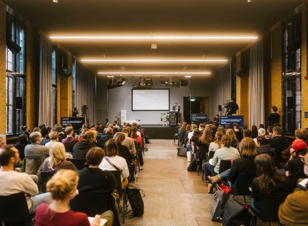 Blick in den Vortragssaal während der kulturBdigital-Konferenz 2022 im bUm in Berlin: Das Publikum blickt zur Bühne, wo Paul Spies, Direktor des Stadtmuseums Berlin gerade an einem Pult spricht.